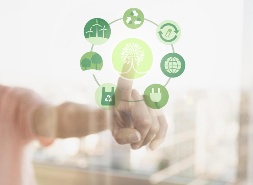 Hand touches green sustainability icons, evoking hope and change.