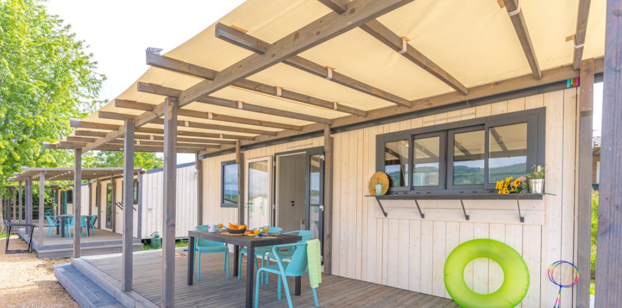 Veranda luminosa con tavolo colorato, relax estivo e natura intorno.