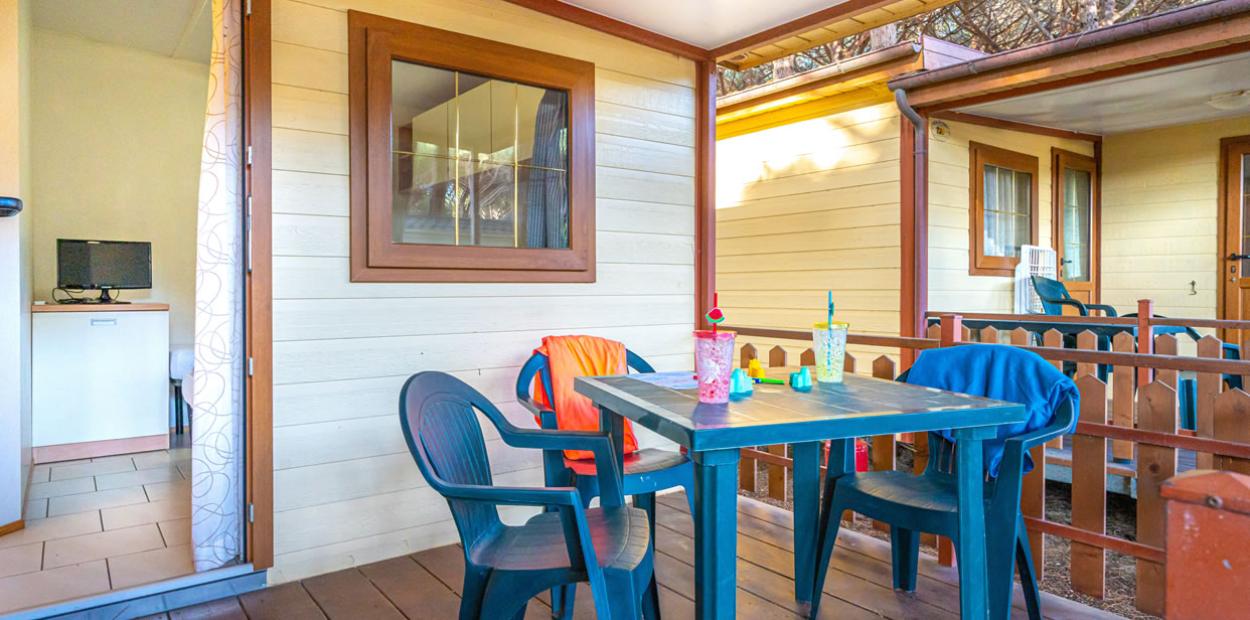 Veranda con tavolo, sedie e bevande, ingresso di una casa mobile.