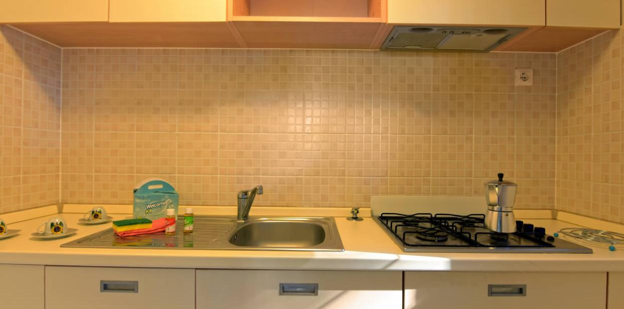 Cucina con lavello, fornello a gas, caffettiera e kit di benvenuto.