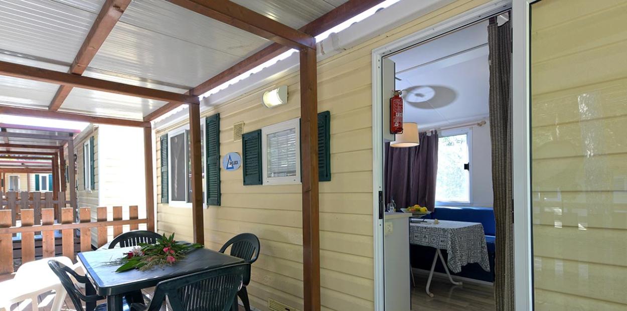 Veranda di una casa mobile con tavolo, sedie e un cestino di dolci.