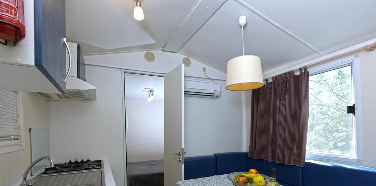 Camera moderna con letto blu, asciugamani bianchi e decorazione con pigna.