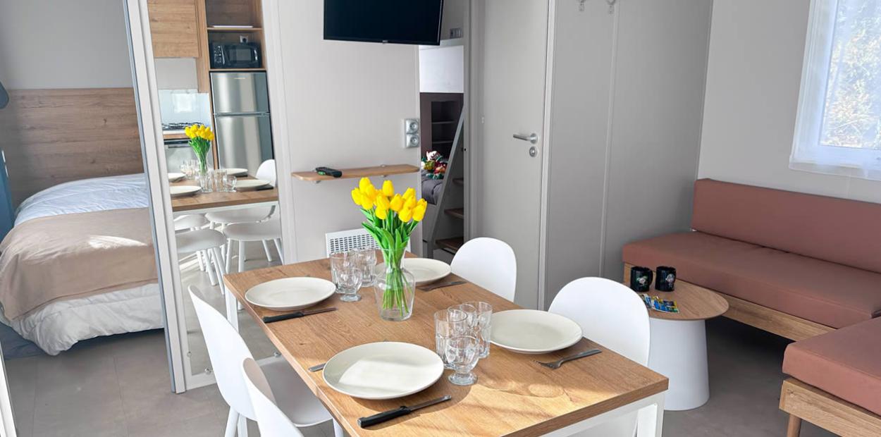 Interno moderno con tavolo apparecchiato, fiori gialli e cucina a vista.