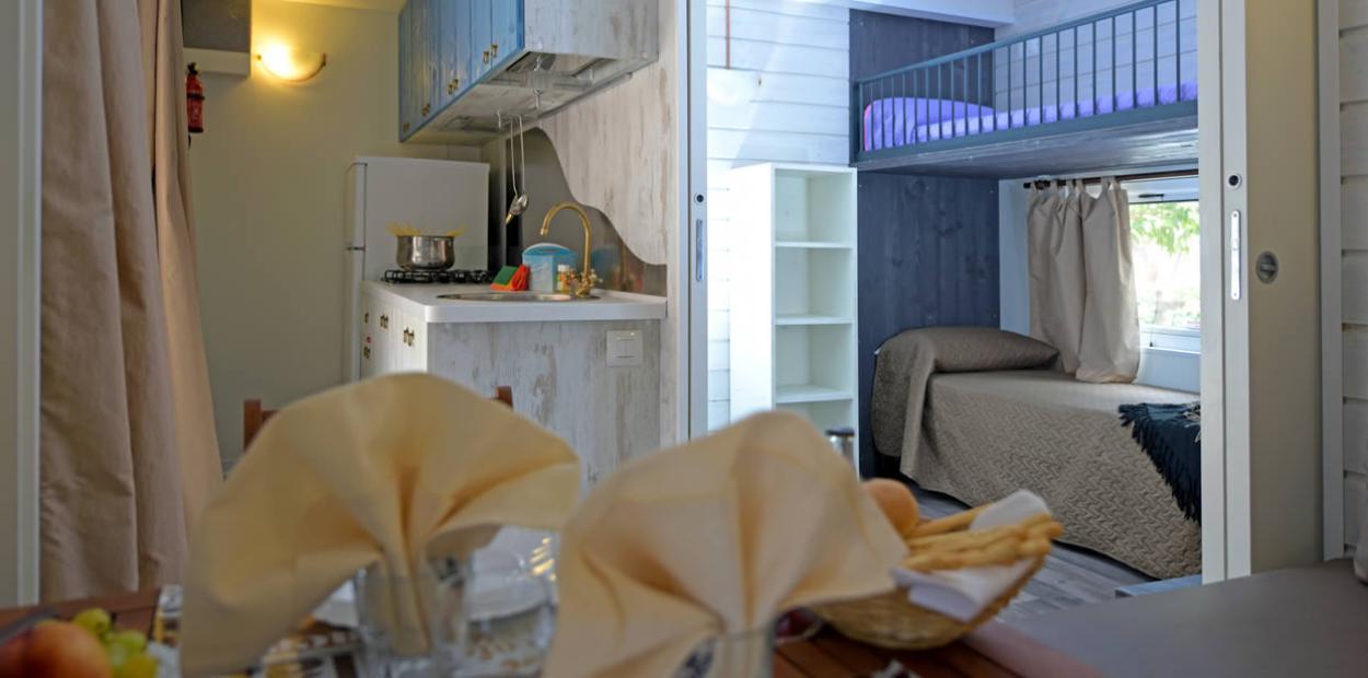 Interno di una casa con cucina compatta e letto a castello.