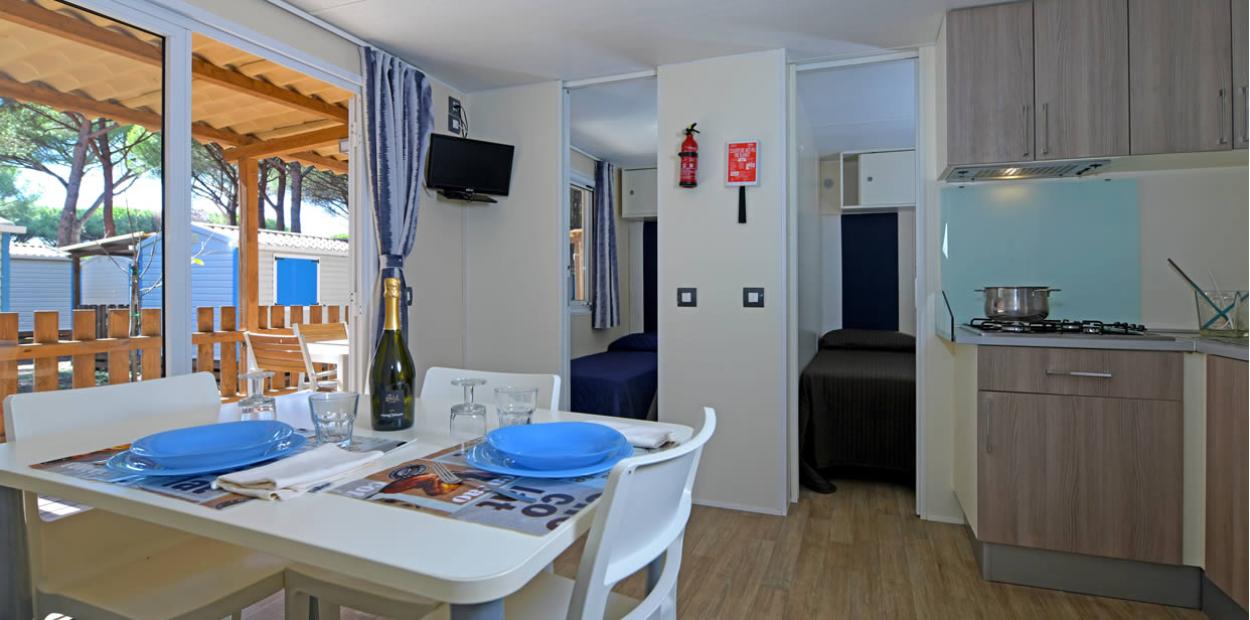 Interno di una casa mobile con cucina, tavolo da pranzo e camera da letto.