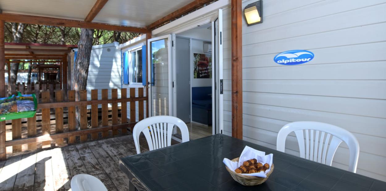 Veranda di una casetta vacanze con tavolo, sedie e cestino di dolci.