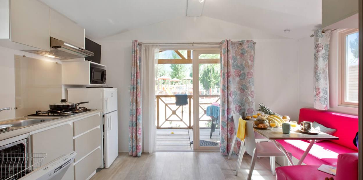 Cucina moderna con tavolo apparecchiato, vista su terrazza esterna, colori vivaci e accoglienti.