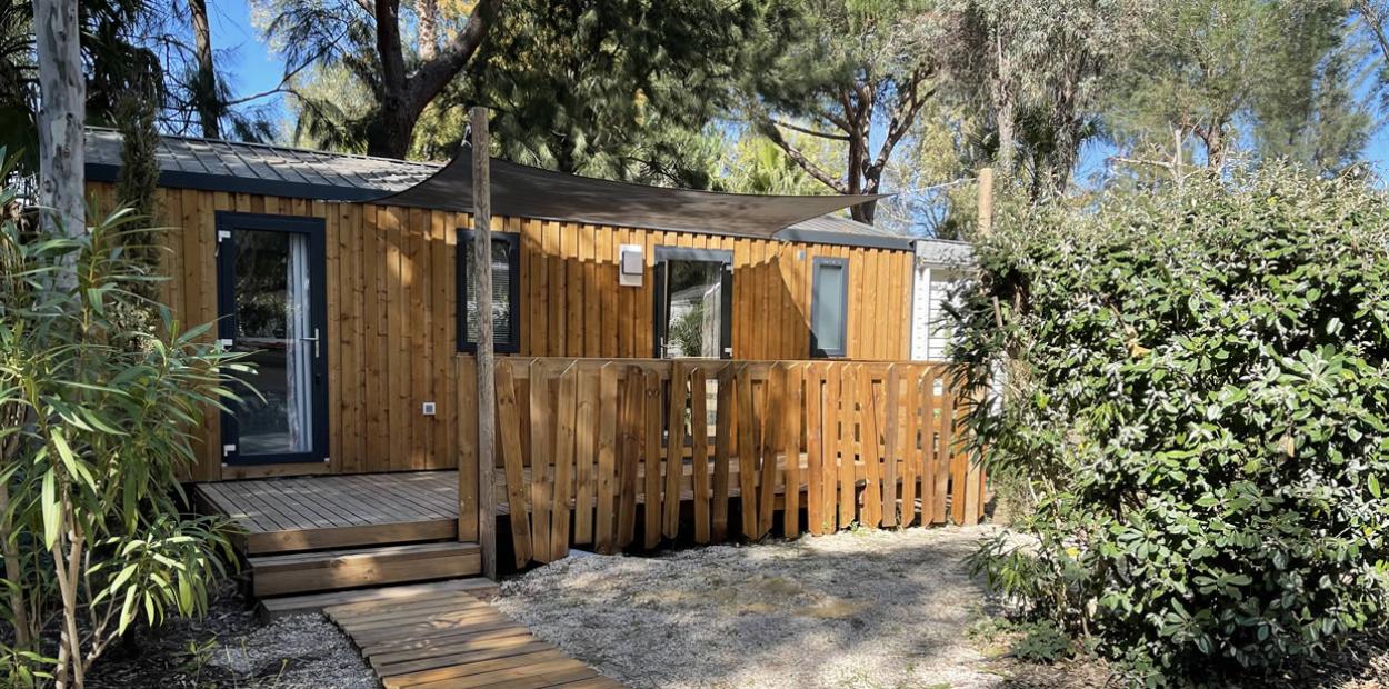 Casetta in legno con veranda, immersa tra gli alberi e circondata da natura.