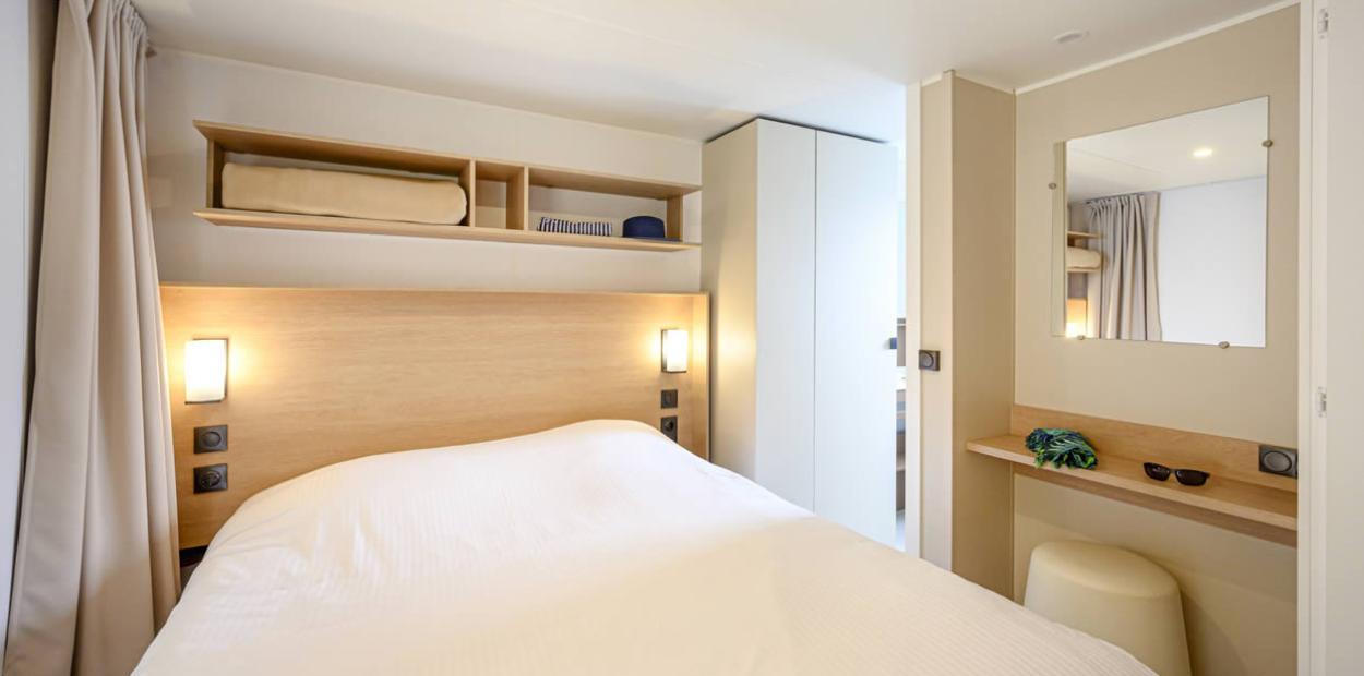 Camera da letto moderna con letto matrimoniale, scaffali e specchio.