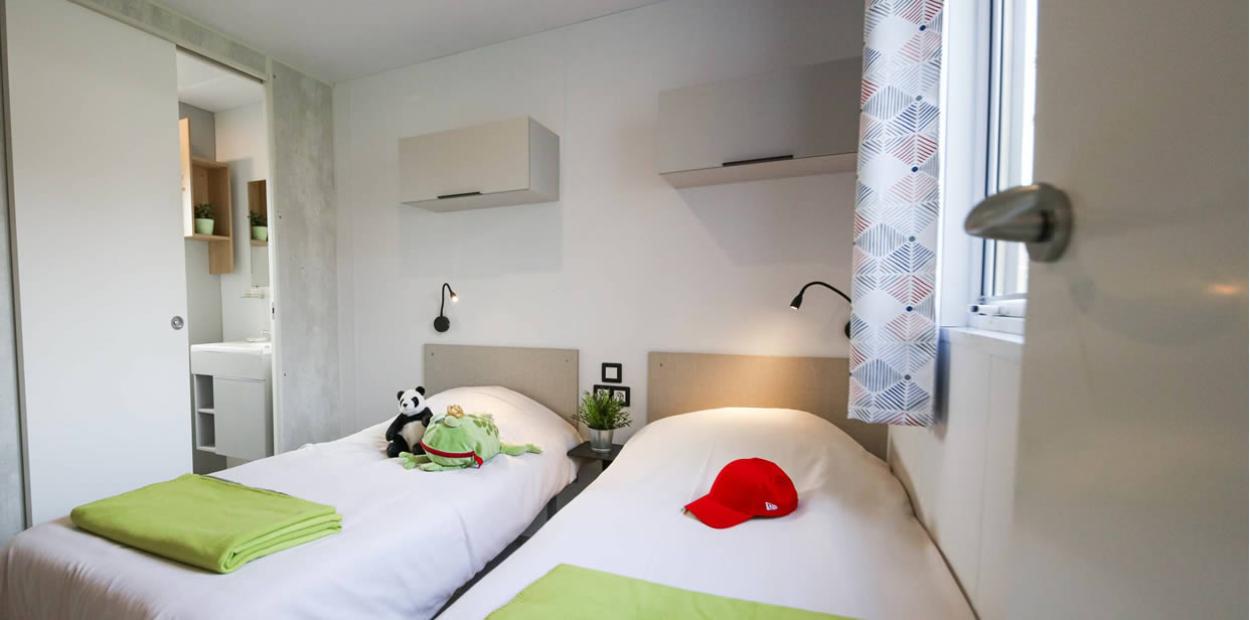 Camera con due letti singoli, decorata con peluche e cappello rosso.