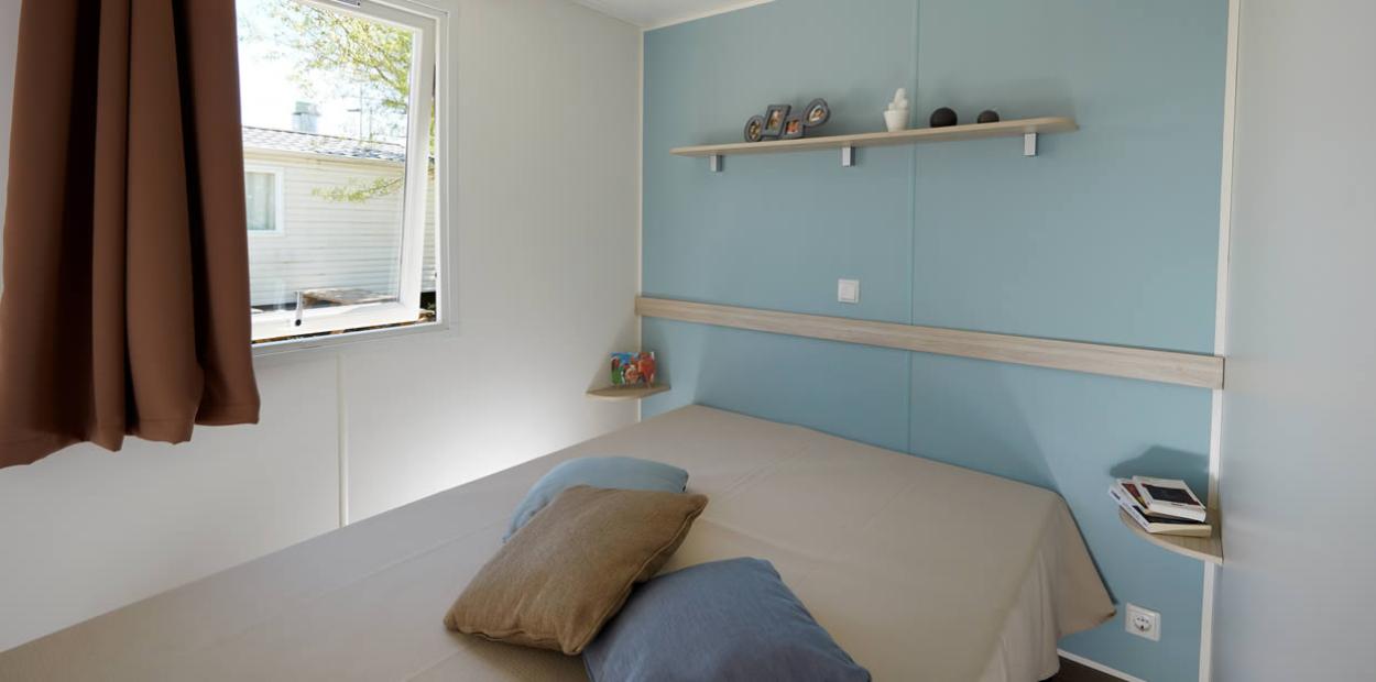 Camera minimalista con letto matrimoniale, mensola e finestra aperta.