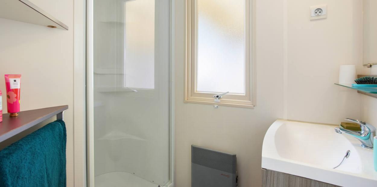 Bagno moderno con doccia, lavandino, asciugamano e finestra opaca.
