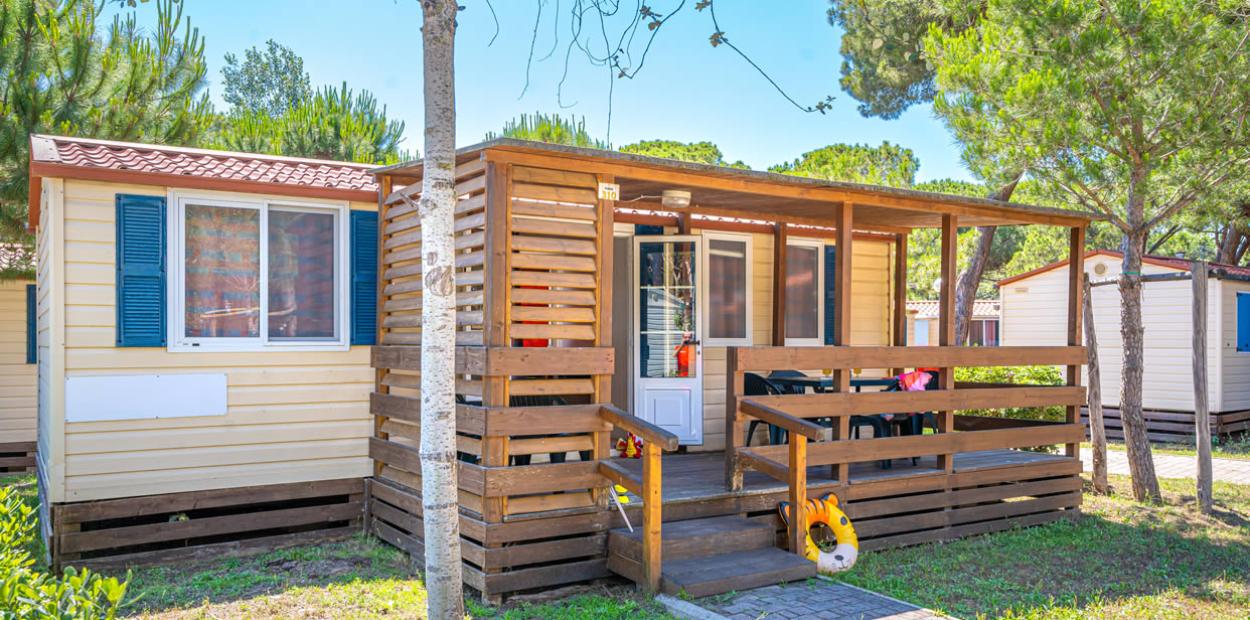 Bungalow con veranda in legno, immerso nel verde, ideale per vacanze all'aperto.