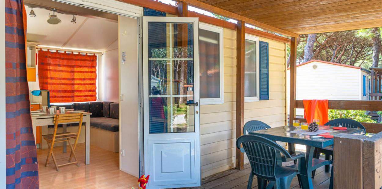 Bungalow con veranda, tavolo all'aperto e interni accoglienti in legno.