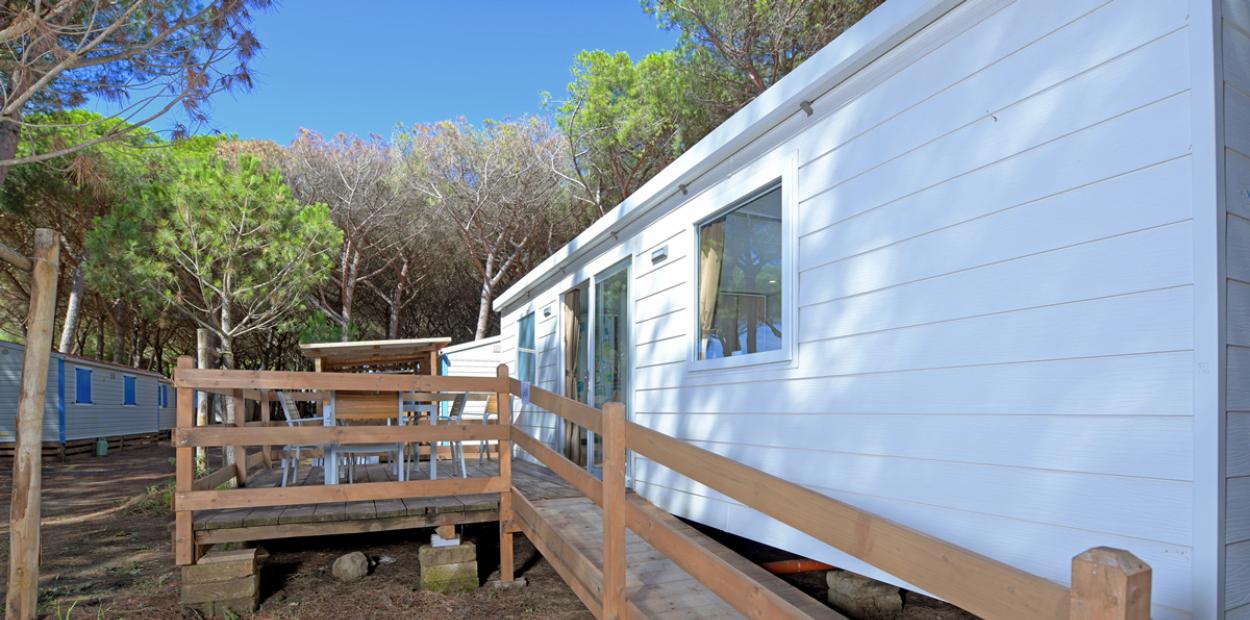Casa mobile bianca con veranda in legno immersa nella natura.