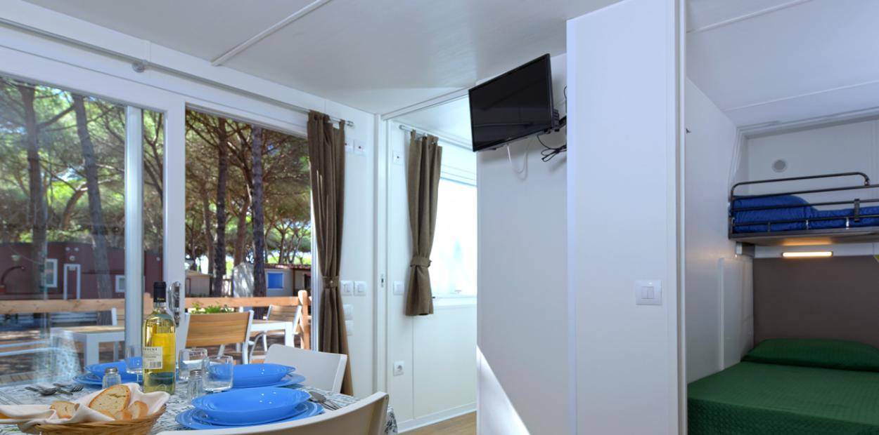 Interno di una casa mobile con tavolo apparecchiato e camera da letto.