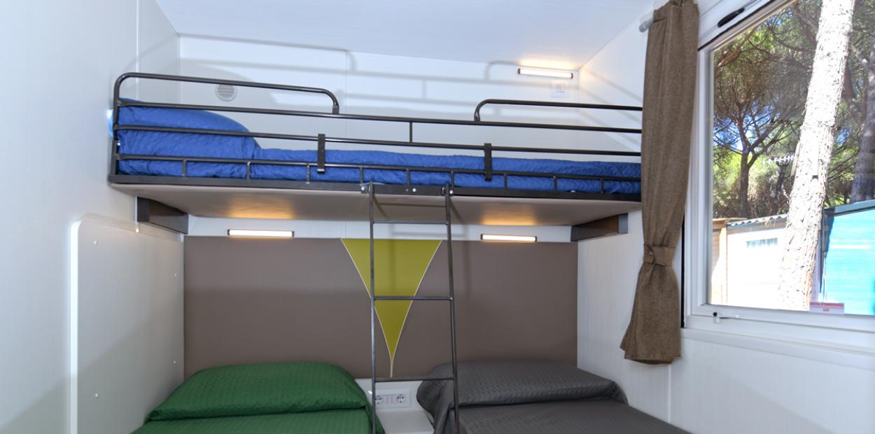 Camera con letto a castello e due letti singoli, finestra con vista esterna.