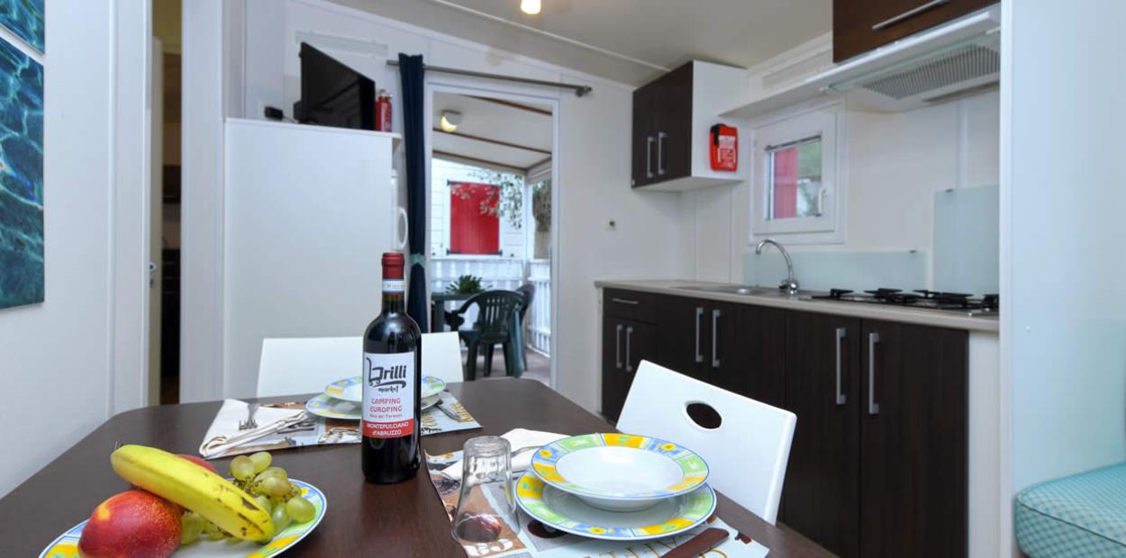 Cucina moderna con tavolo apparecchiato, frutta e vino in un ambiente accogliente.