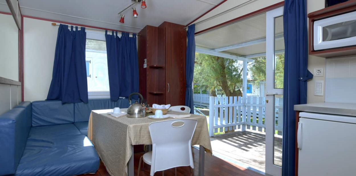 Interno di una casa mobile con cucina, tavolo e veranda esterna.