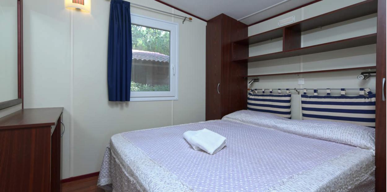 Camera da letto con letto matrimoniale, finestra e arredi in legno scuro.