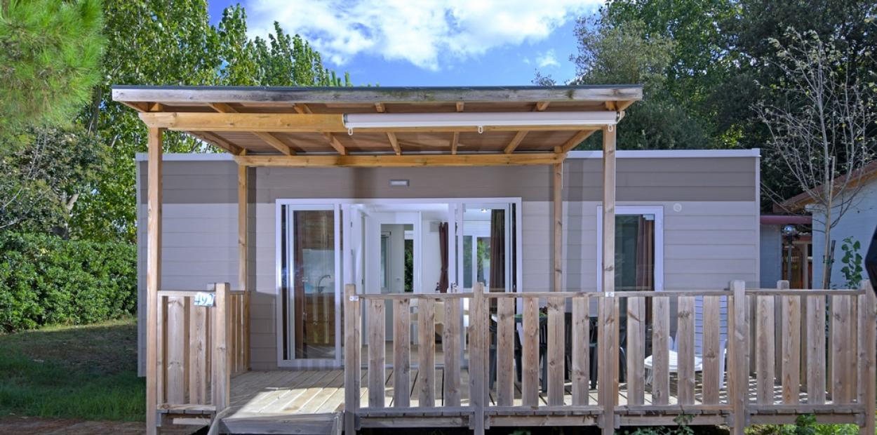 Casa mobile con veranda in legno, immersa nel verde.