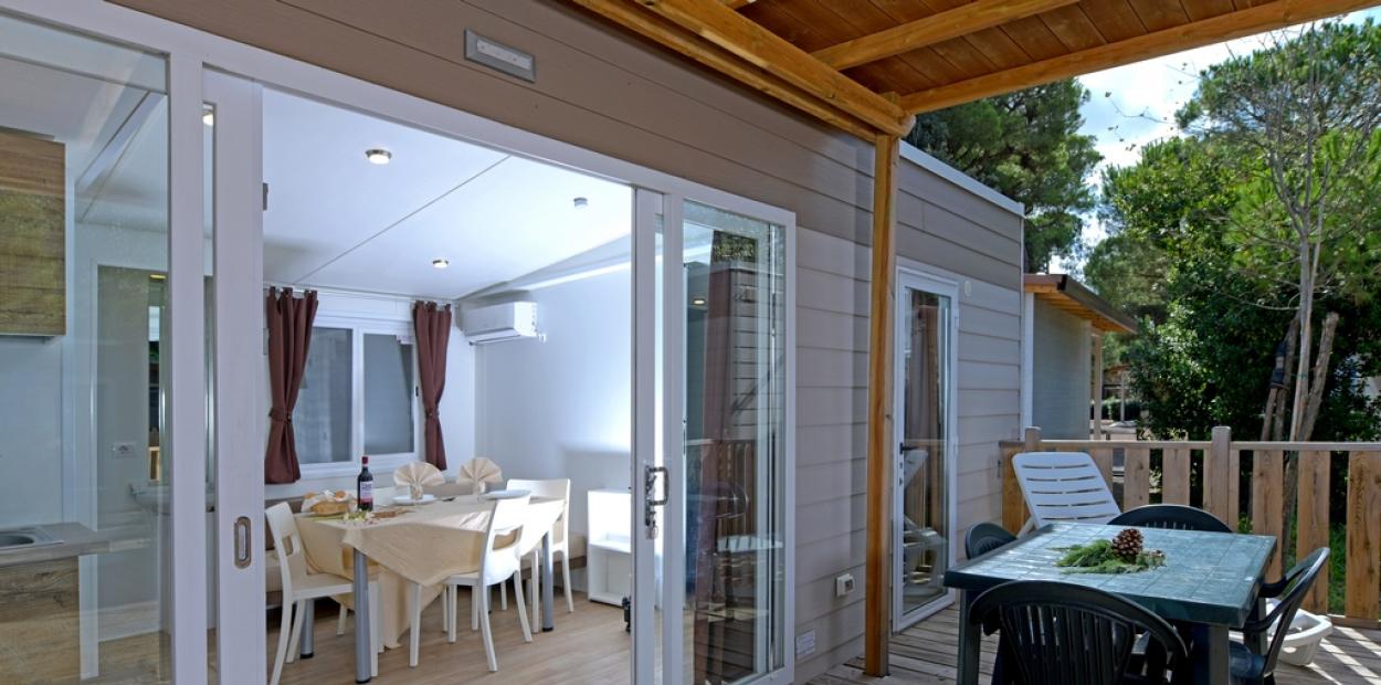 Moderna veranda con tavolo all'aperto, accesso a soggiorno luminoso e arredato.