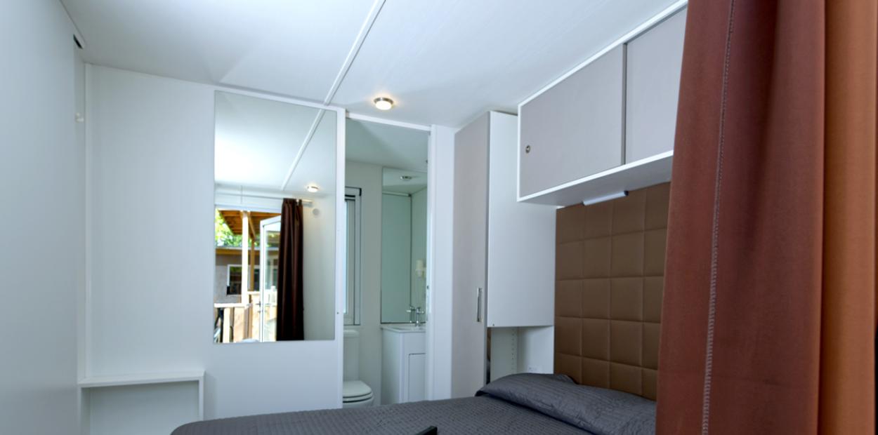 Camera moderna con letto matrimoniale, specchio, asciugamani e bagno privato.
