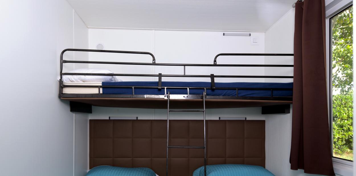 Camera con letto a castello e due letti singoli, copriletti blu.