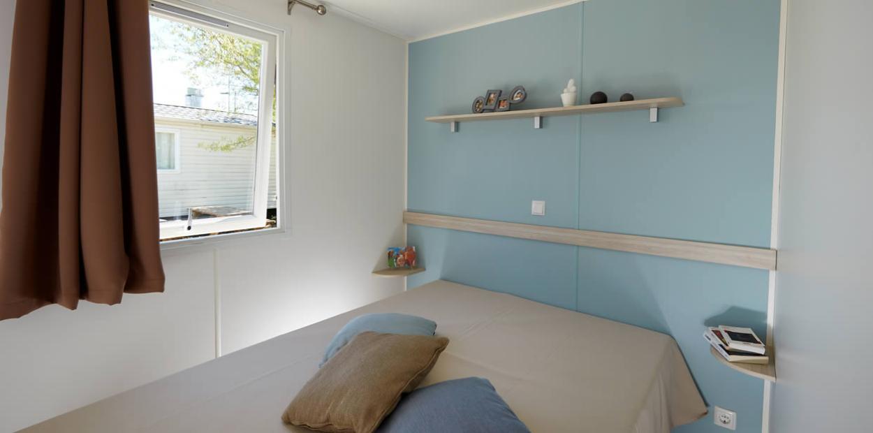 Camera minimalista con letto matrimoniale, mensola e finestra aperta.
