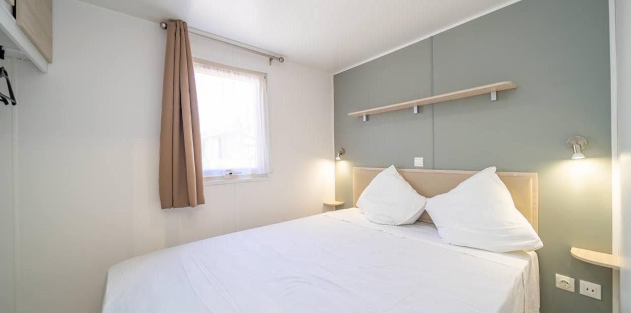 Camera da letto moderna con letto matrimoniale, pareti chiare e finestra luminosa.
