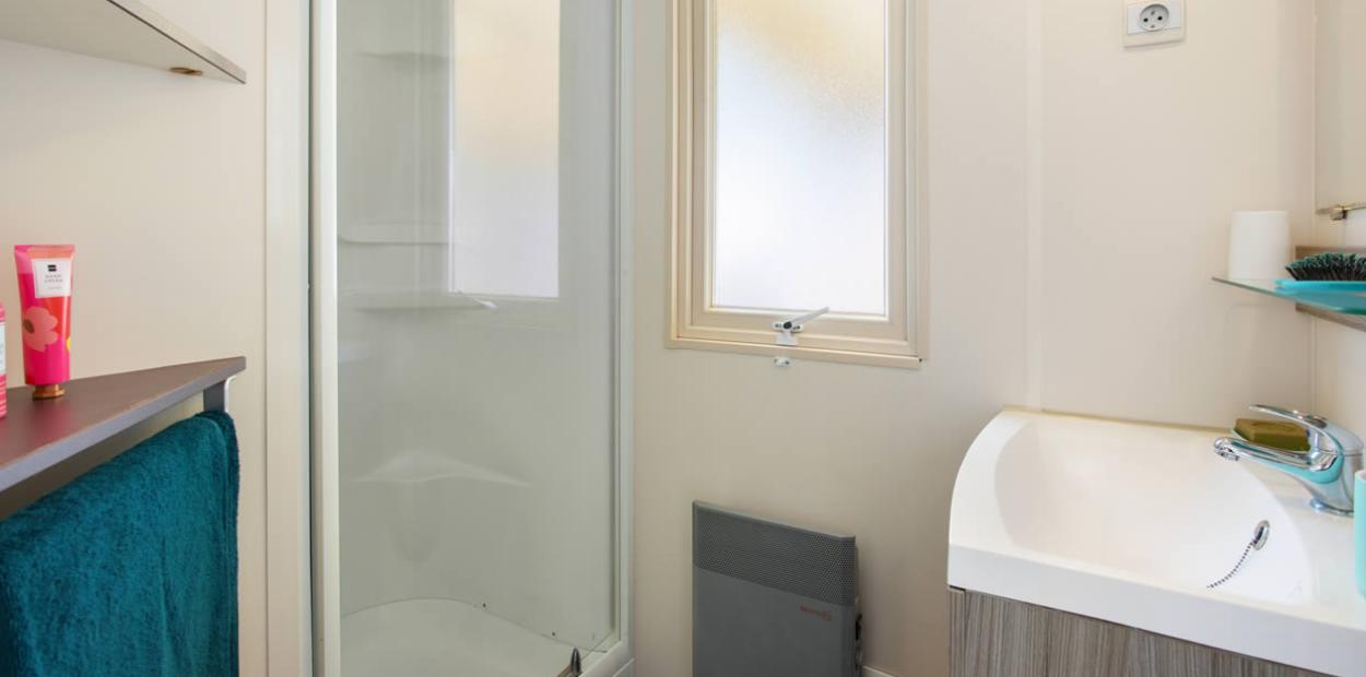 Bagno moderno con doccia, lavandino, finestra e accessori colorati.