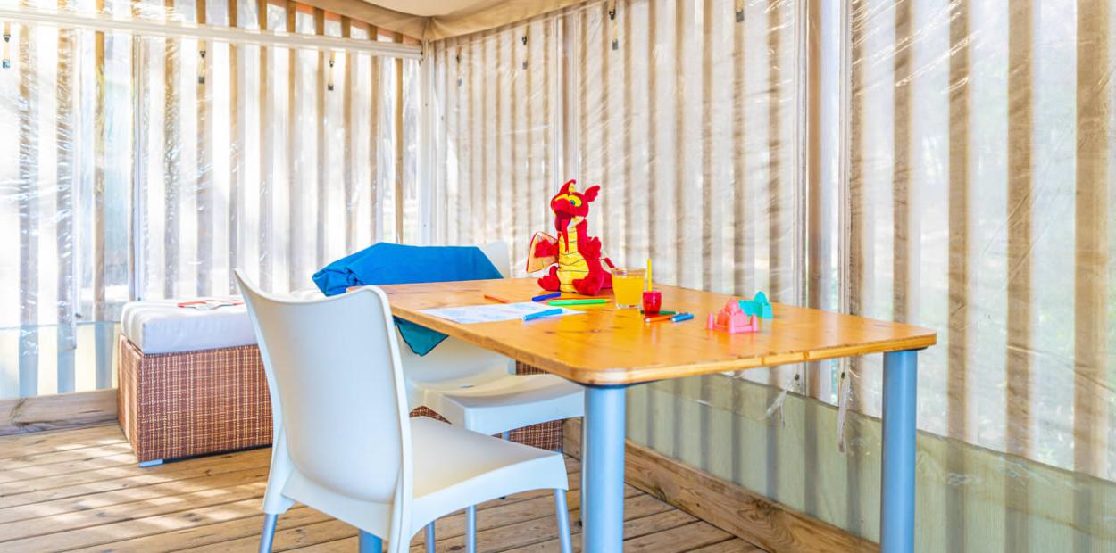 Spazio luminoso con tavolo, sedia, giochi e bevanda su pavimento in legno.