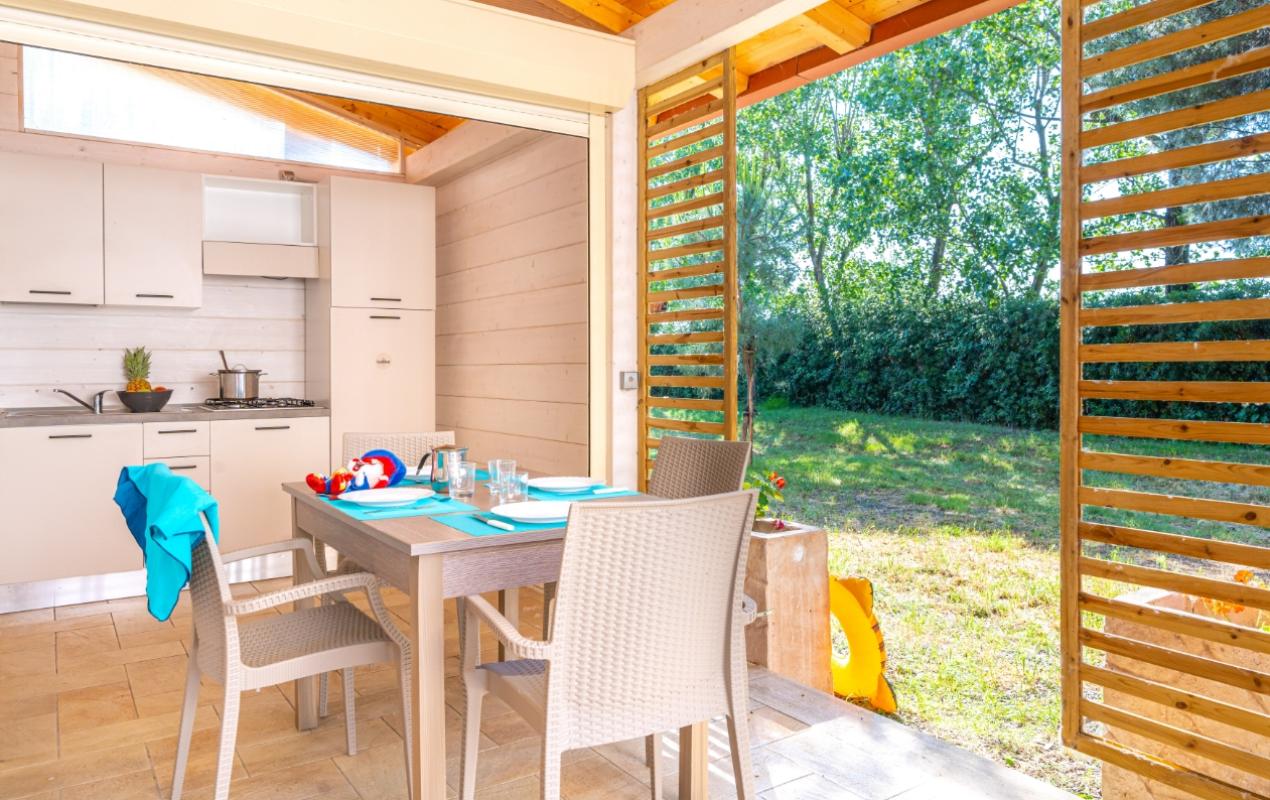 Cucina luminosa con tavolo apparecchiato, vista sul giardino attraverso porte scorrevoli in legno.