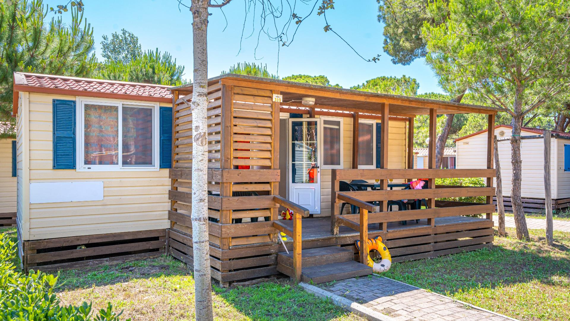 Casetta in legno con veranda, immersa nel verde, ideale per vacanze rilassanti.