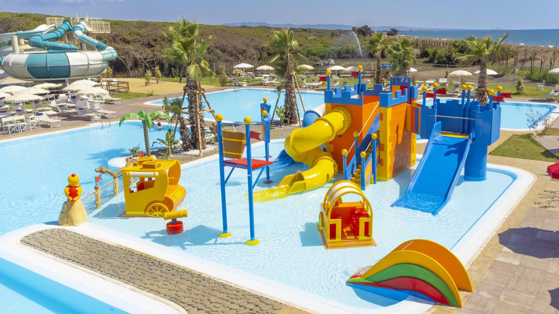 Parco acquatico con scivoli colorati e giochi per bambini, vicino alla spiaggia.