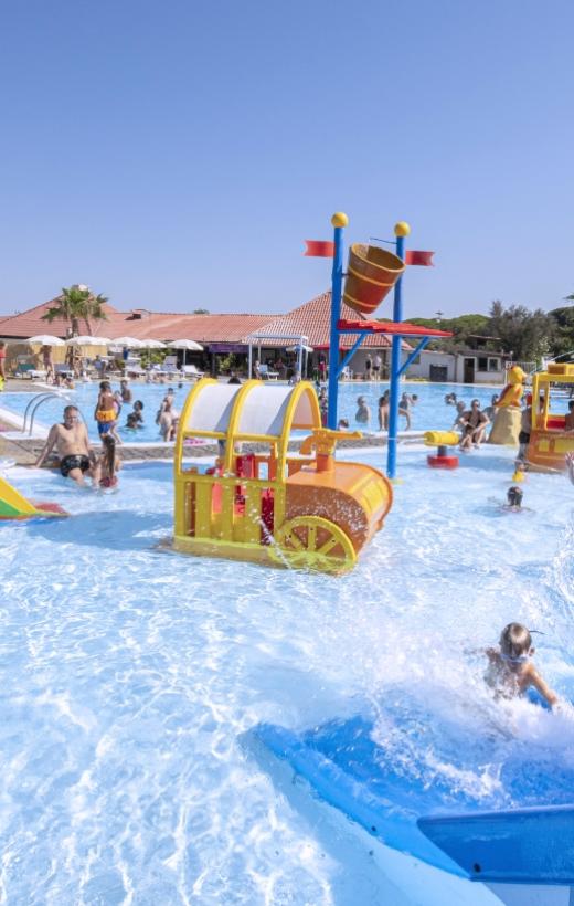 Parco acquatico con giochi colorati e bambini che si divertono in piscina.