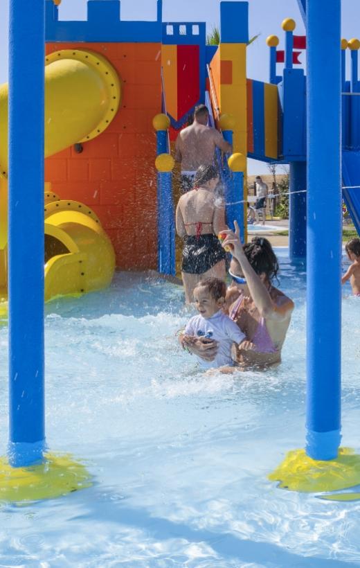 Famiglia si diverte in piscina con scivoli colorati.