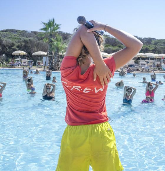 Famiglie e bambini giocano e si divertono in una piscina all'aperto sotto il sole.
