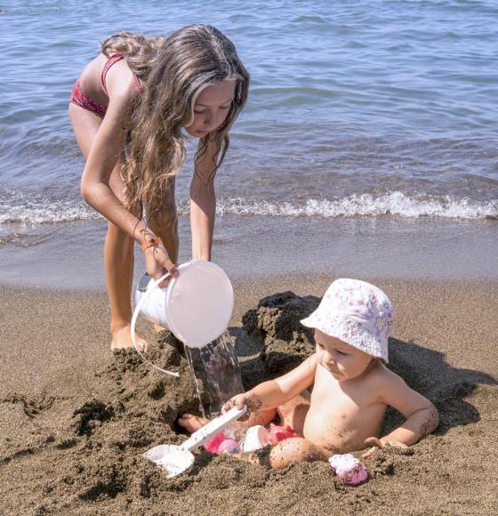 Spiaggia sabbiosa con ombrelloni blu e lettini sotto un cielo limpido.