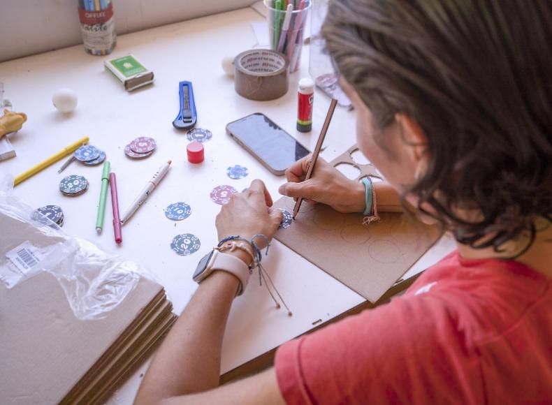 Persona crea oggetti artigianali su un tavolo con materiali e strumenti vari.