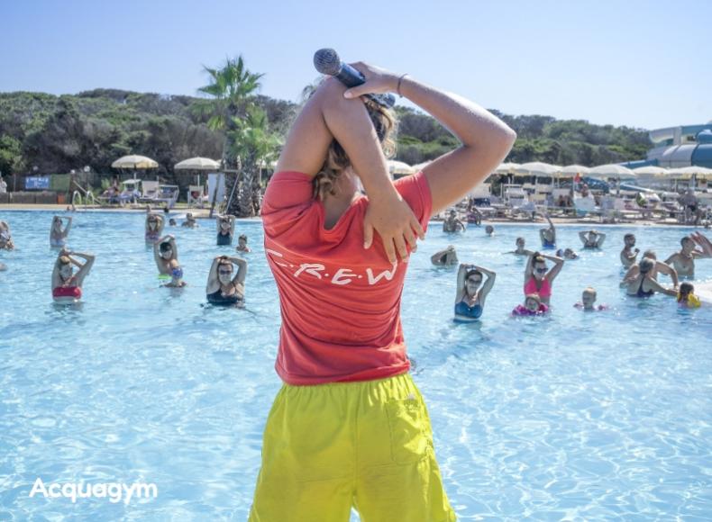 Istruttore guida lezione di acquagym in piscina con gruppo di partecipanti.