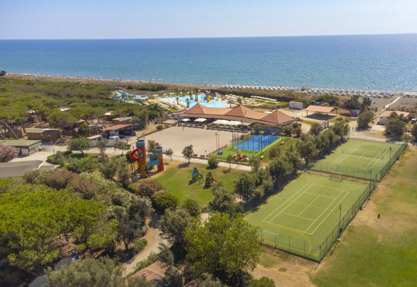 Complesso sportivo con campi da tennis, area giochi e campo da padel immerso nel verde.