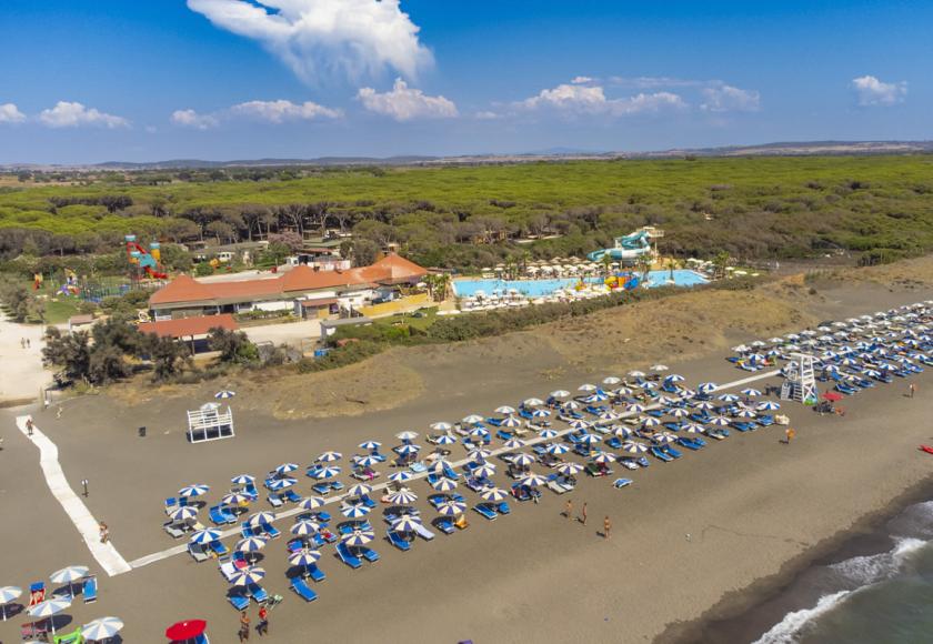 Spiaggia affollata con bagnanti, ombrelloni e mare calmo sotto un cielo sereno.